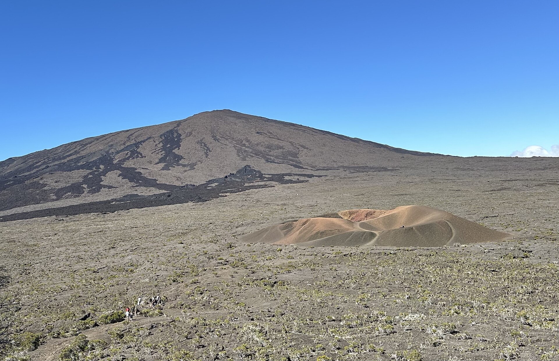 Le Formica Leo, petit cône de scories rouges au pied du Piton de la Fournaise, avec le volcan en arrière-plan