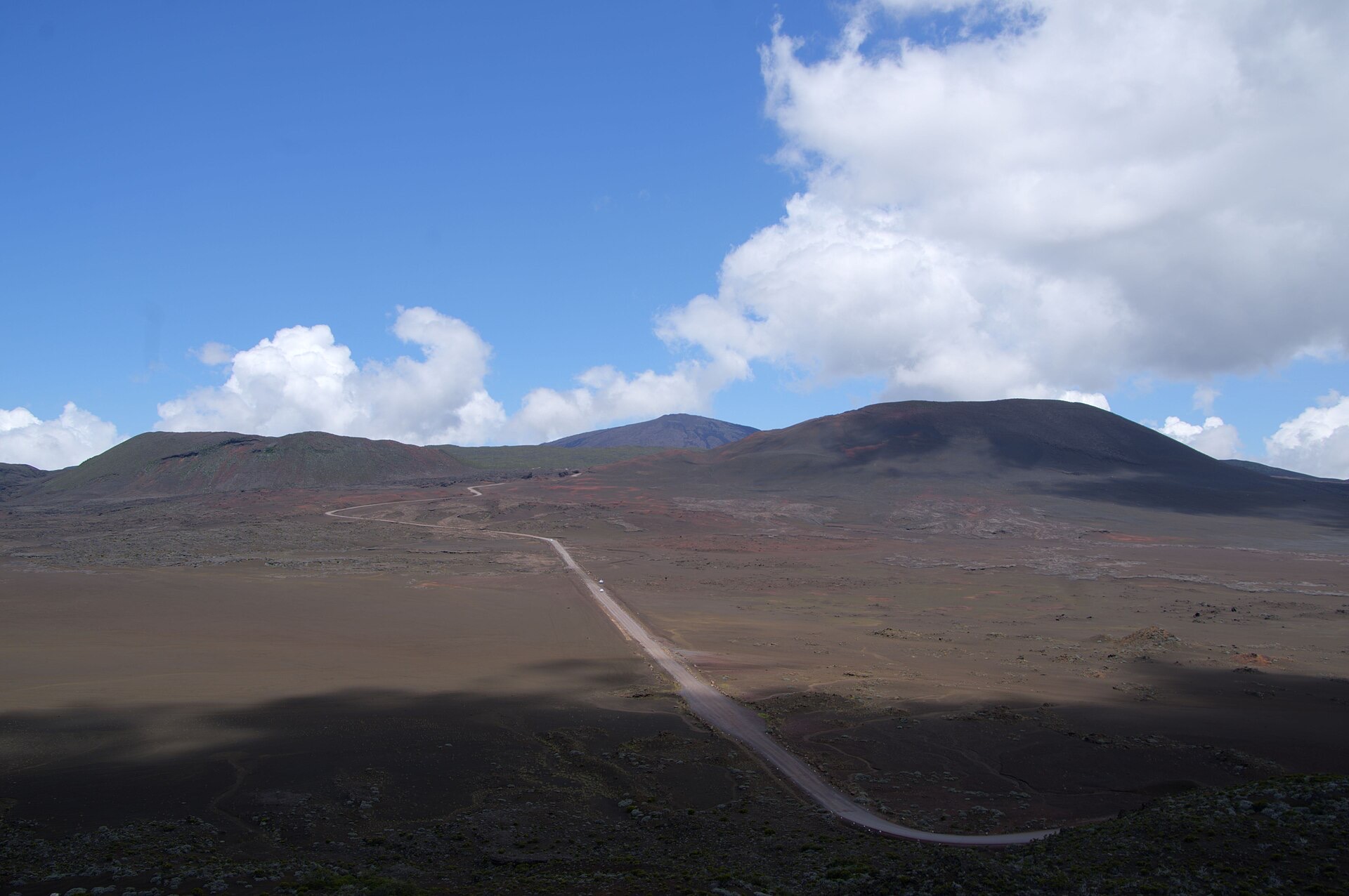La Plaine des Sables à La Réunion : piste de scories traversant un plateau nu, cônes volcaniques et remparts au fond