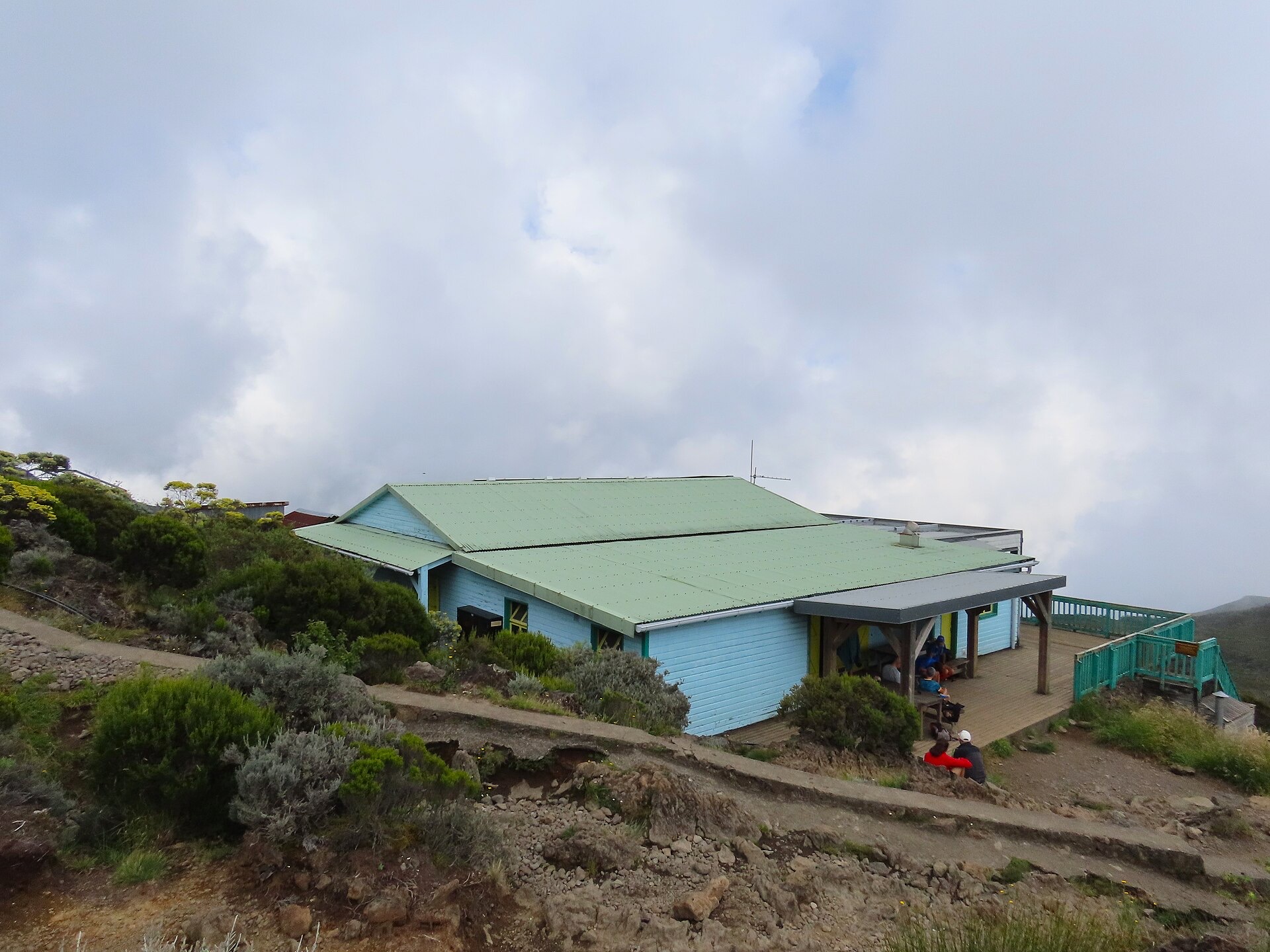 Le refuge de la Caverne Dufour, bâtiment bas au toit vert posé sur la lande d'altitude sous les nuages