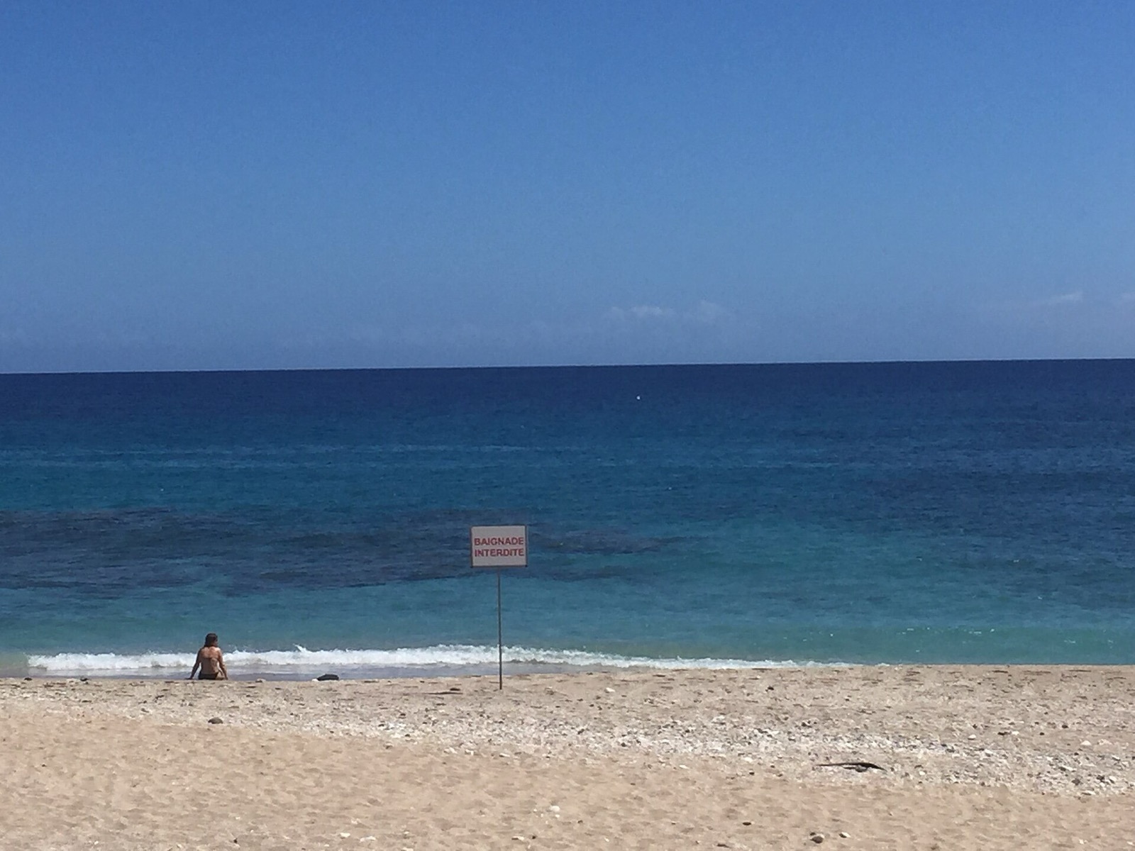 Panneau d'interdiction de baignade planté sur la plage de Boucan Canot, à La Réunion