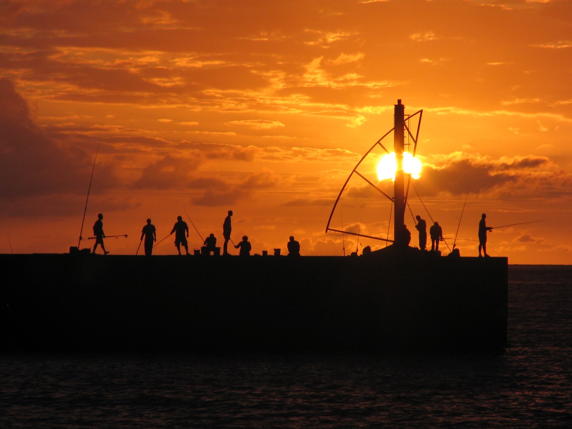 Coucher de soleil à Saint-Gilles les Bains, silhouettes de pêcheurs sur la jetée du port