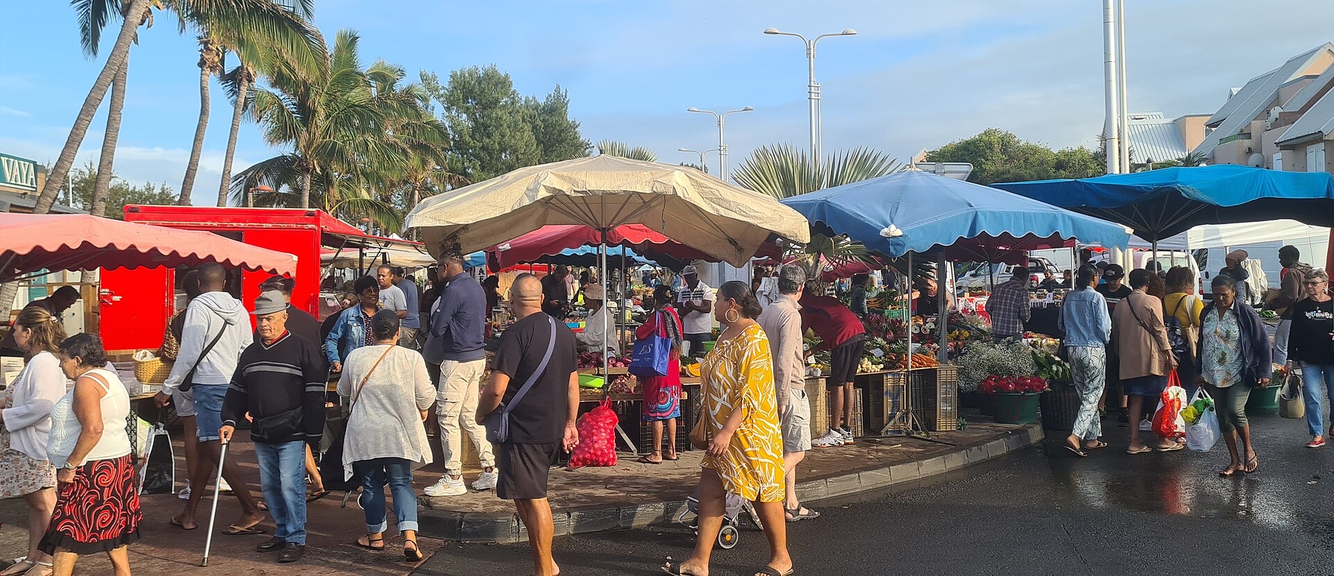 Allée du marché forain de Saint-Pierre de La Réunion, étals sous les parasols et clients de dos